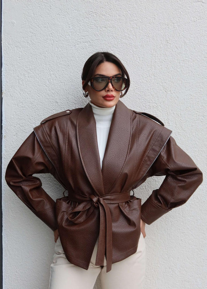 Adoptez une allure chic et affirmée avec cette veste en similicuir marron, pensée pour sublimer la silhouette tout en offrant confort et style au quotidien.
Sa coupe ceinturée permet de marquer délicatement la taille, ajoutant une touche féminine et moderne. La matière effet cuir est légèrement matelassée, apportant structure et élégance à la pièce.
Le col plié (folded collar) offre un look raffiné, tandis que les épaulettes intégrées ajoutent du caractère et une belle ligne d’épaule. La veste est entière